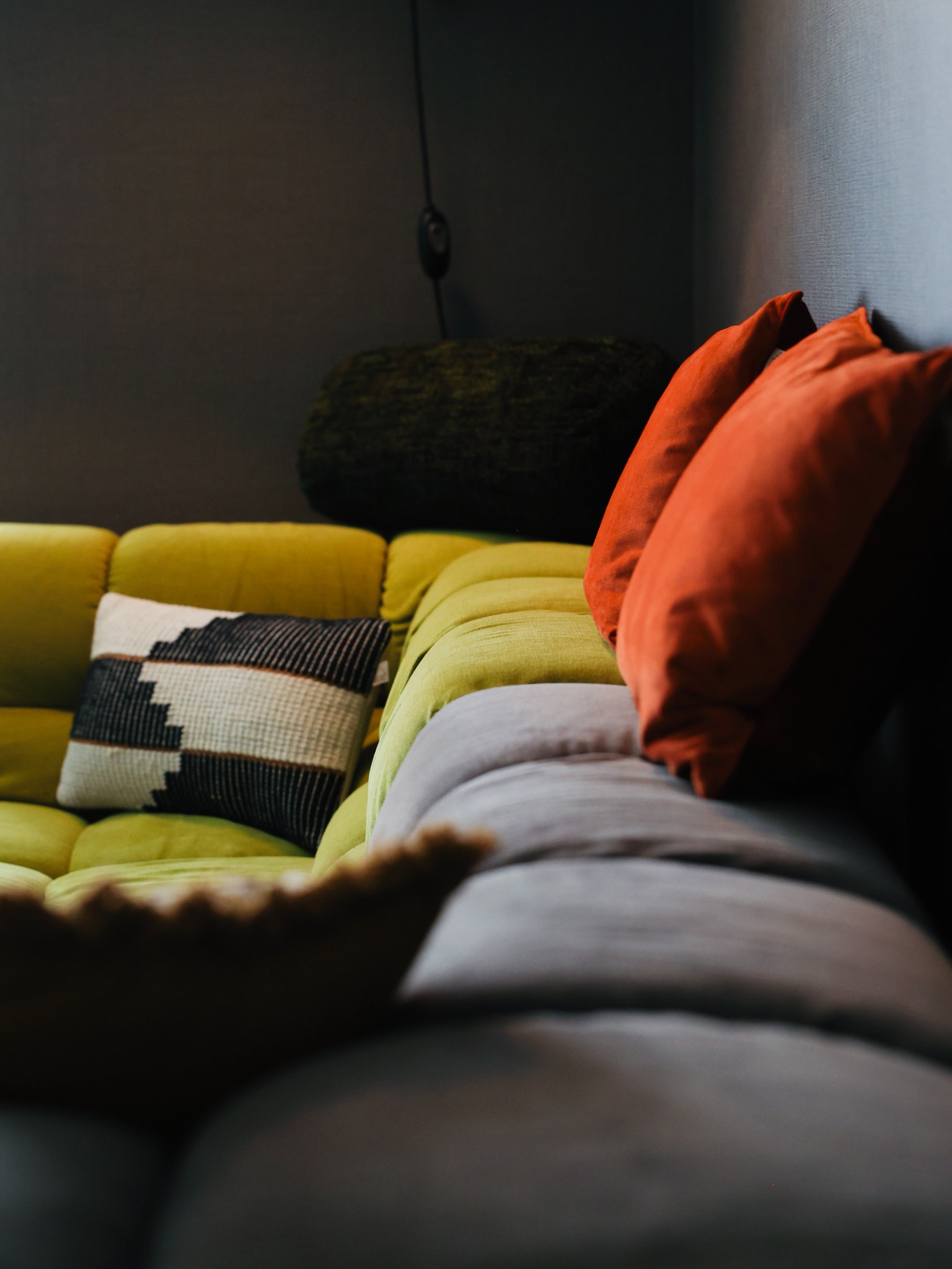 Wohnbereich mit grünem Sofa und orangefarbenen Kissen