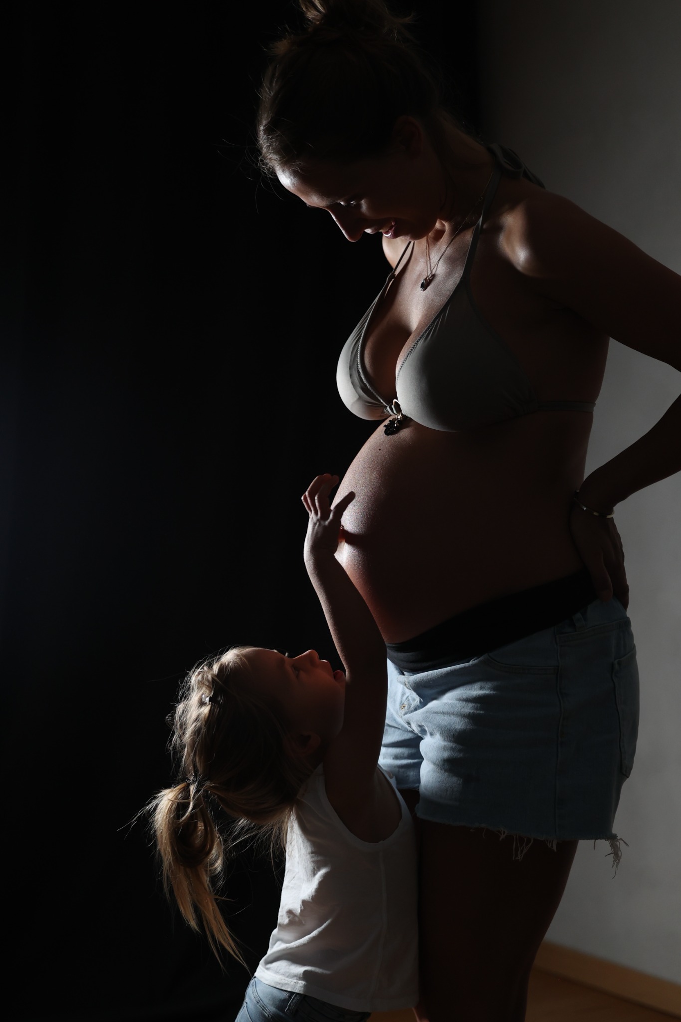 Kind berührt liebevoll den Babybauch seiner Mutter