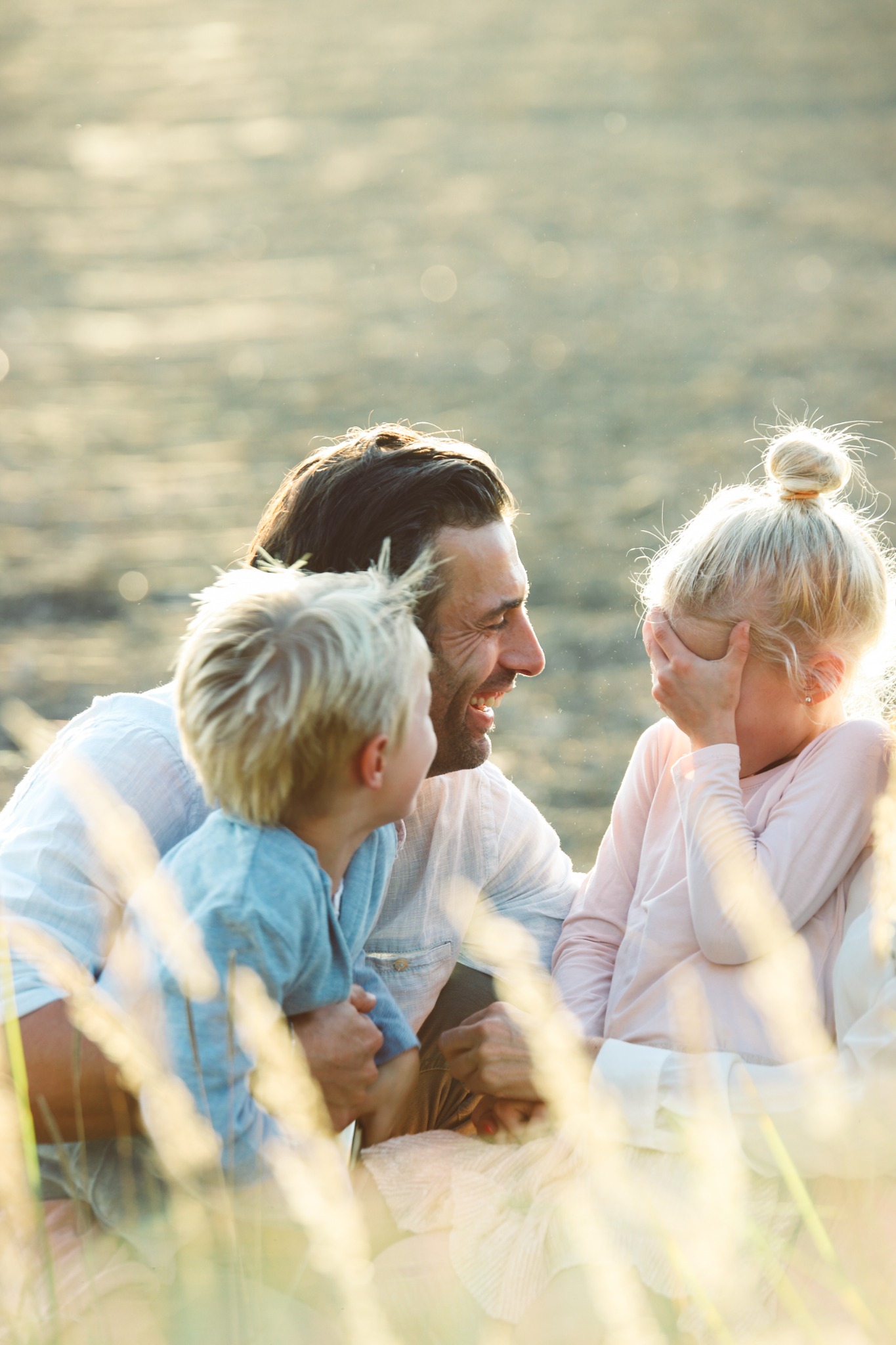 Vater lacht mit seinen beiden Kindern im warmen Abendlicht