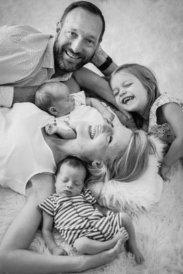 Fröhliche Familie mit zwei kleinen Babys bei einem natürlichen Newborn-Shooting