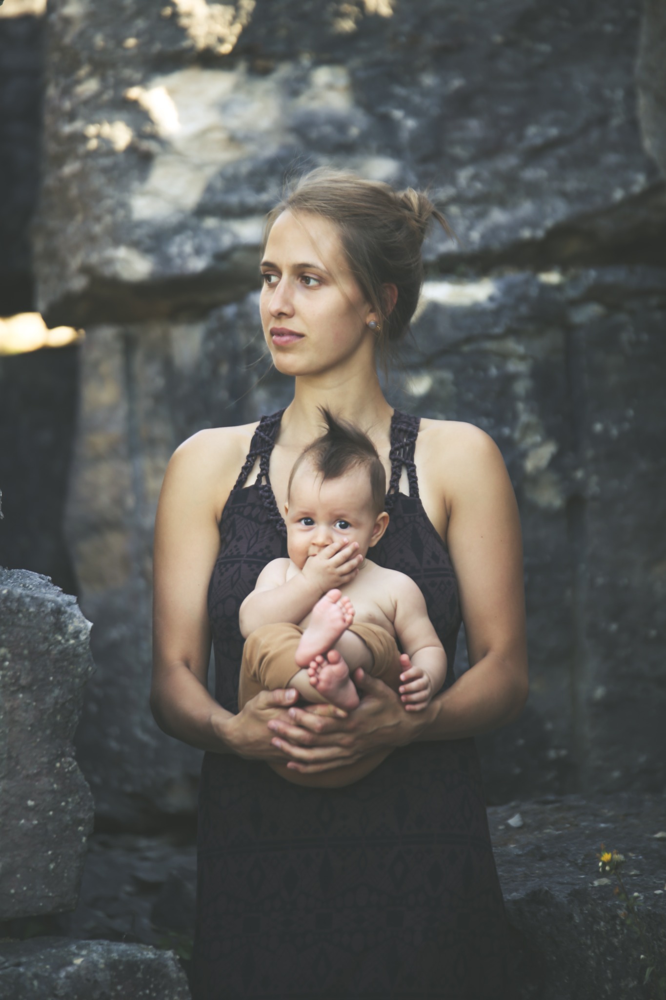 Mutter hält ihr Baby bei einem stimmungsvollen Shooting zwischen Felsen im Steinbruch